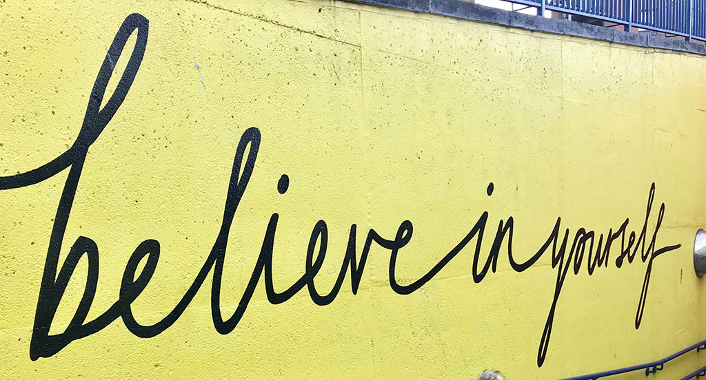 Immagine anteprima sezione Ricerca e Selezione : scritta in stile calligrafico che recita "Believe in yourself" di colore nero su muro a sfondo giallo